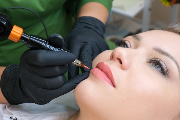 Jonge vrouw met permanente make-up op haar lippen bij de schoonheidssalon. Natuurlijke groene achtergrond