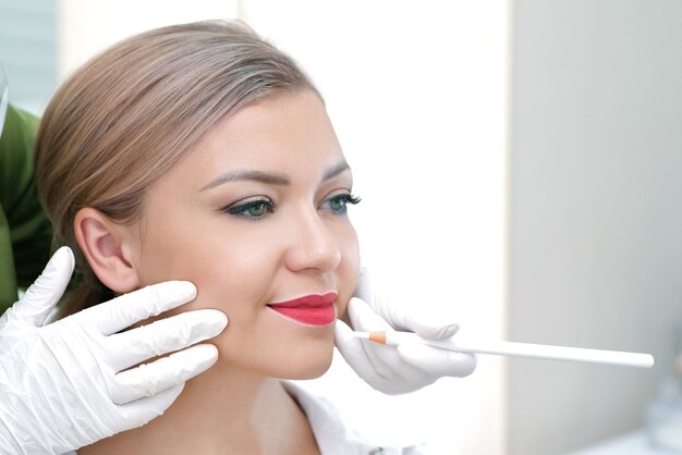 Jonge vrouw met permanente make-up op haar lippen bij de schoonheidssalon.