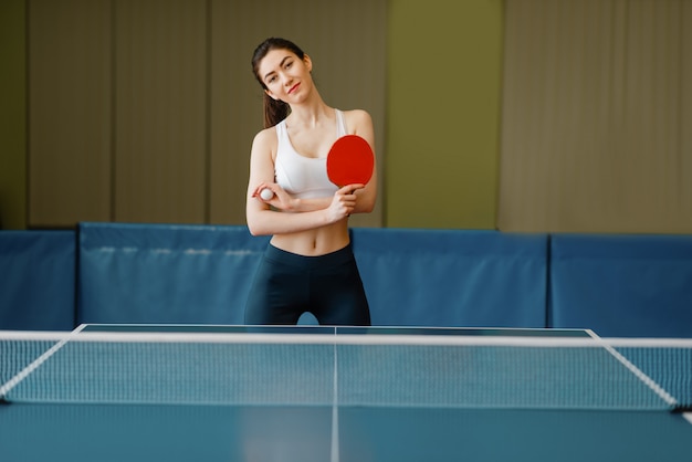 Jonge vrouw met pingpongracket aan de tafel