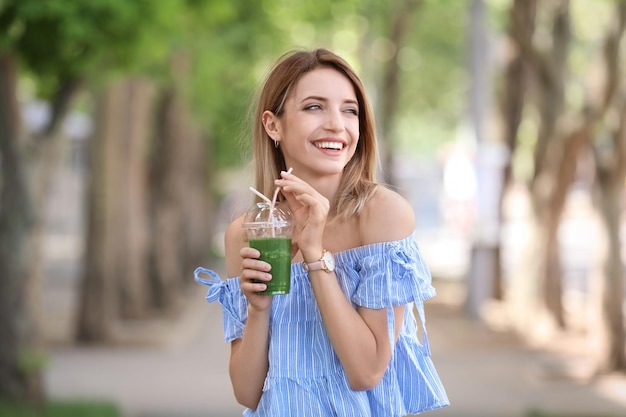 Jonge vrouw met plastic beker gezonde smoothie buiten