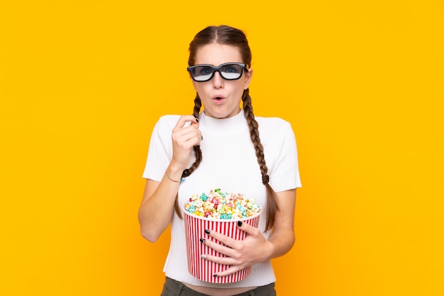 Jonge vrouw met popcorns over geïsoleerde muur