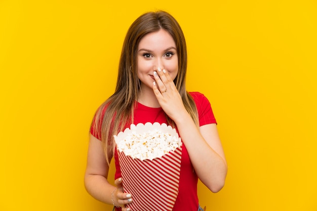 Jonge vrouw met popcorns over roze muur met verrassingsgelaatsuitdrukking