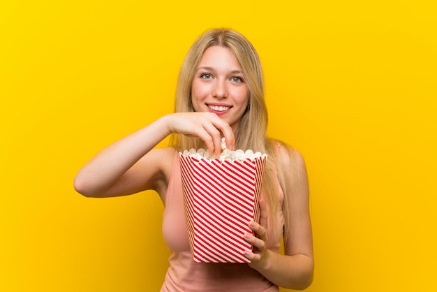 Jonge vrouw met popcorns over roze muur