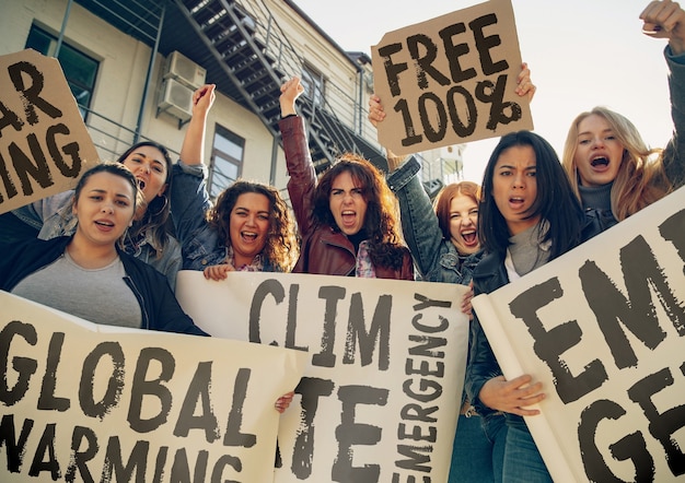 Jonge vrouw met poster voor mensen die protesteren tegen klimaatverandering op straat. Bijeenkomst over probleem in ecologie, milieu, opwarming van de aarde, industriële invloed, klimaatnoodsituatie.