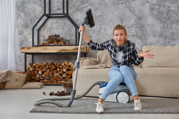 Jonge vrouw met reinigingsapparatuur klaar om huis schoon te maken, zittend op de bank. professioneel schoonmaakserviceconcept, kopieer ruimte. vermoeidheid