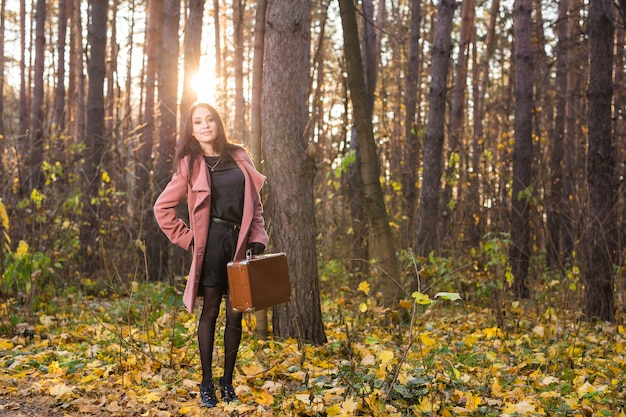 Jonge vrouw met retro koffer in herfst park