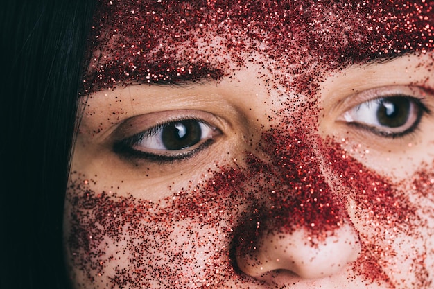 Jonge vrouw met rode glitter op haar gezicht poseren