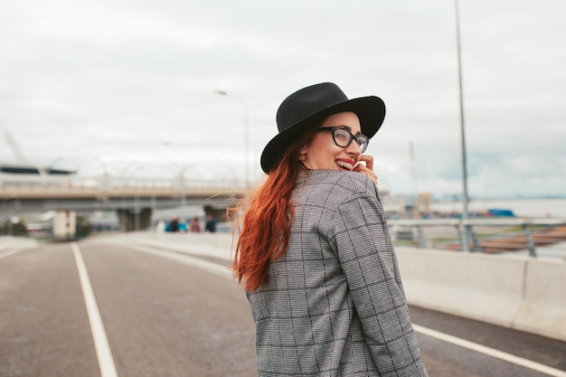 Jonge vrouw met rood haar die lacht met een beugel