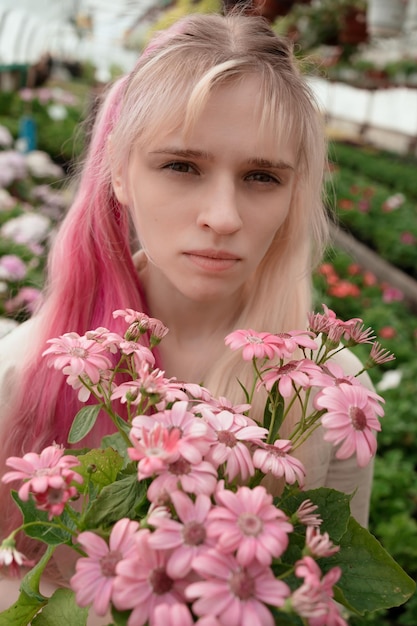 Jonge vrouw met roze en blond haar met roze bloemen in de tuin