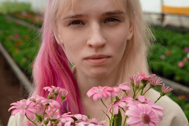 Jonge vrouw met roze en blond haar met roze bloemen in de tuin
