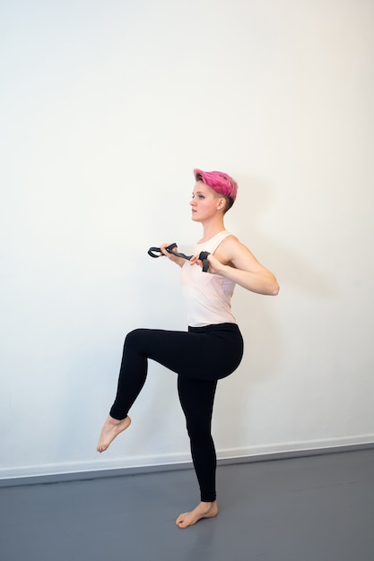 Jonge vrouw met roze haar doet een rugoefening met een rubberen schokdemper