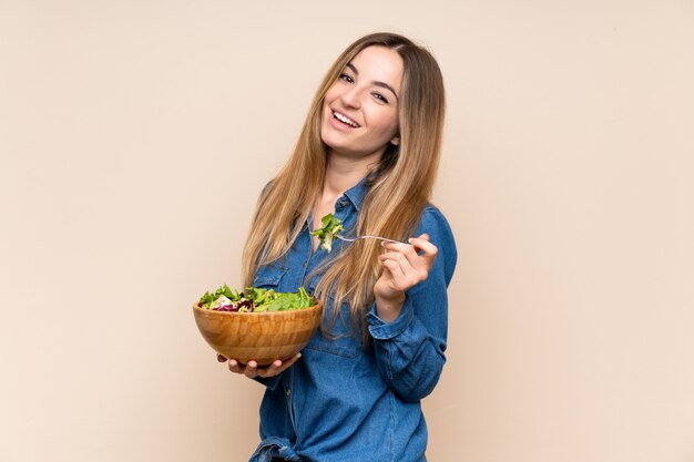 Jonge vrouw met salade over geïsoleerde achtergrond