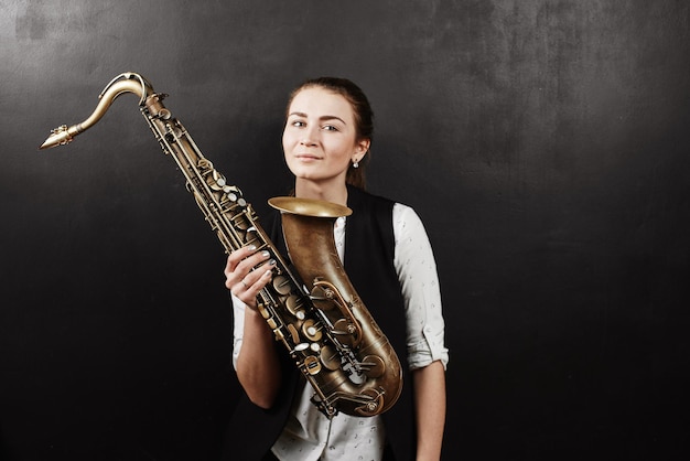 Jonge vrouw met saxofoon op zwarte achtergrond