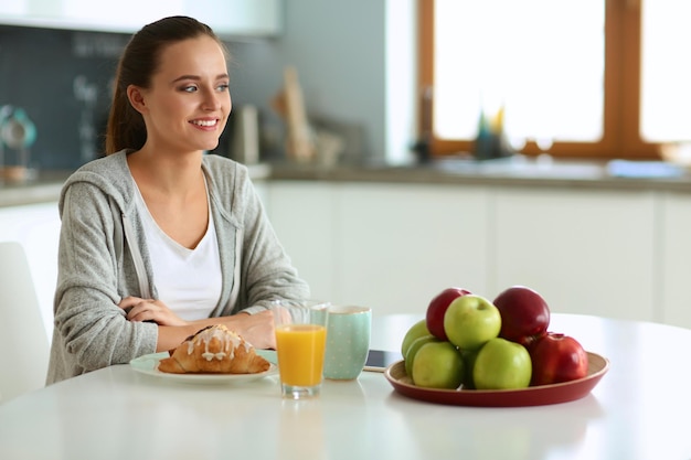 jonge vrouw met sinaasappelsap en tablet in de keuken