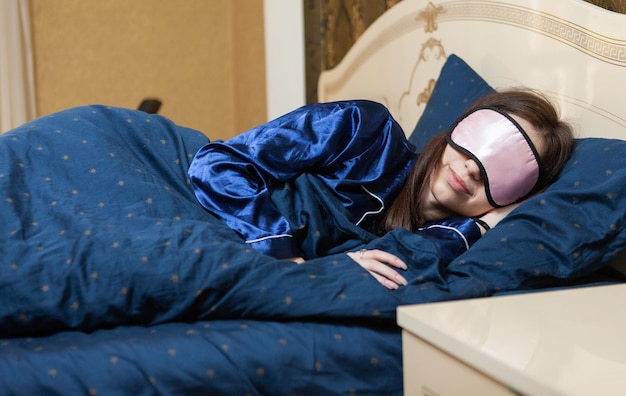 Jonge vrouw met slaapmasker slapen op het bed