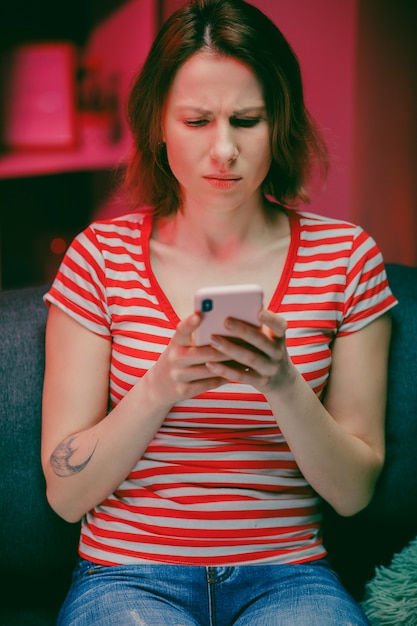 Jonge vrouw met slimme telefoon kijken naar mobiel scherm met behulp van mobiele apps om te winkelen