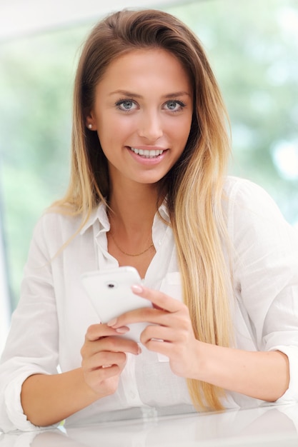 Foto jonge vrouw met smartphone in de keuken