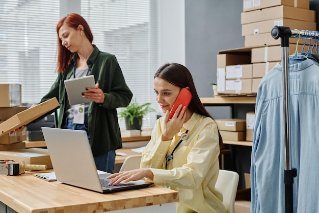 Jonge vrouw met smartphone op het gehoor laptop scherm kijken