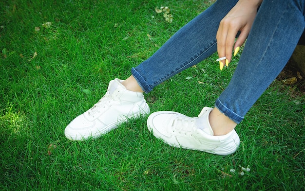 Jonge vrouw met stijlvolle sneakers op groen gras