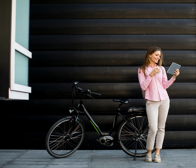 Jonge vrouw met tablet en e-bike buiten