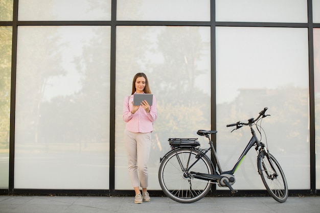 Jonge vrouw met tablet en e-bike buiten