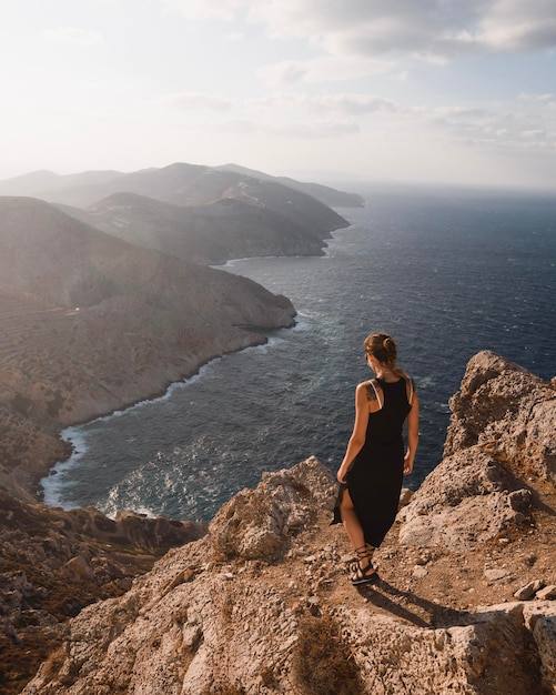 Foto jonge vrouw met tatoeages die bij zonsondergang langs de kliffen van het griekse eiland folegandros loopt