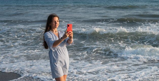 Jonge vrouw met telefoon aan zee.