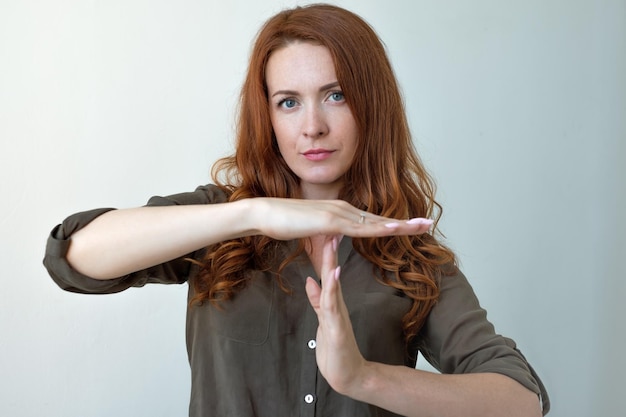 Jonge vrouw met time-out handgebaar gefrustreerd schreeuwen om te stoppen geïsoleerd op grijze muur achtergrond