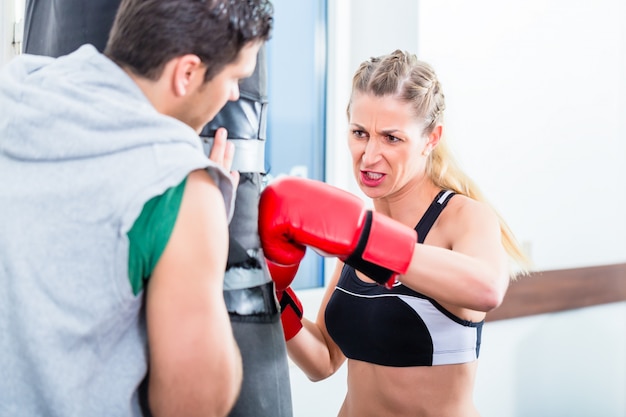 Jonge vrouw met trainer in het in dozen doen sparring