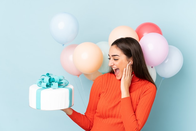 Jonge vrouw met veel ballonnen geïsoleerd op blauwe achtergrond