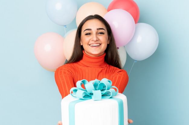 Jonge vrouw met veel ballonnen op blauw