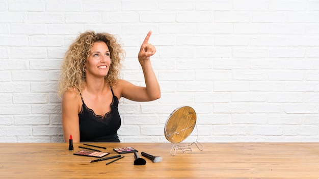 Jonge vrouw met veel make-up penseel in een tabel op transparant scherm aan te raken