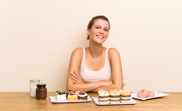 Jonge vrouw met veel verschillende minicakes in lijst het lachen