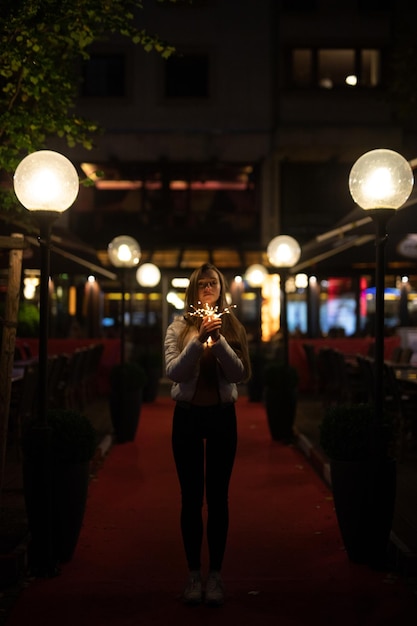 Jonge vrouw met verlichte verlichtingstoerusting bij de ingang van een restaurant