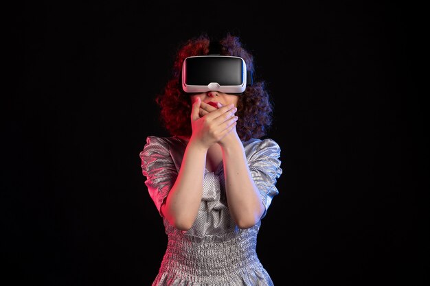 Jonge vrouw met virtual reality headset op donkere ondergrond