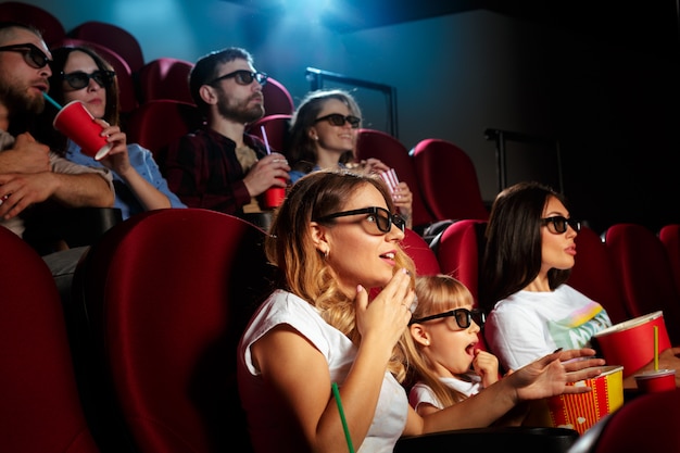 Jonge vrouw met vrienden die op film in bioskoop letten