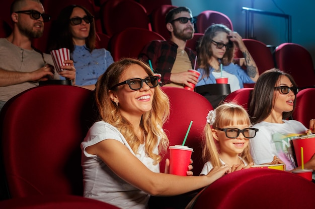 Jonge vrouw met vrienden kijken naar film in de bioscoop