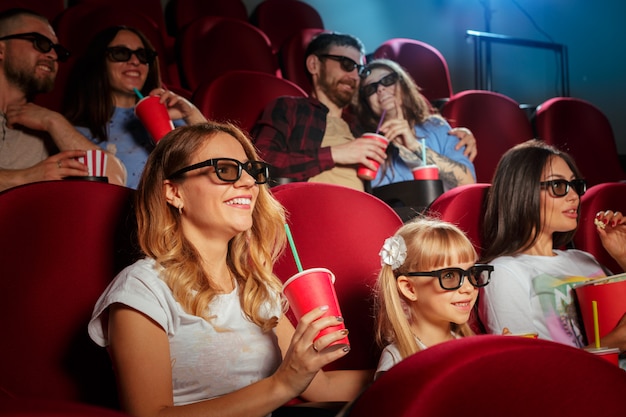 Jonge vrouw met vrienden kijken naar film in de bioscoop