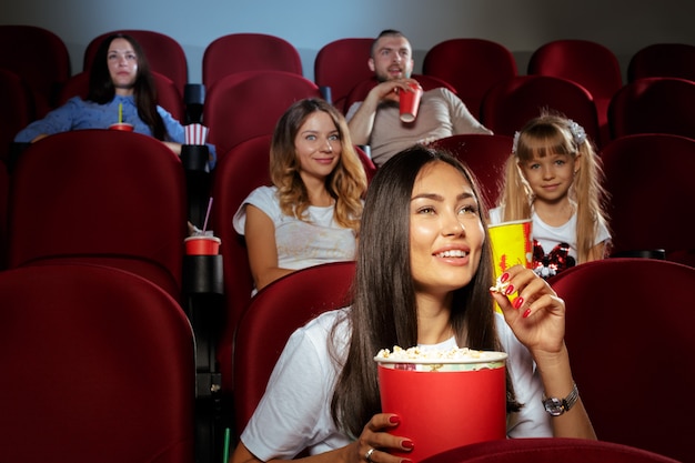 Jonge vrouw met vrienden kijken naar film in de bioscoop