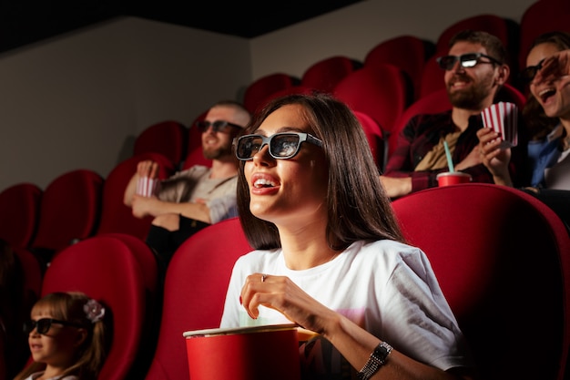 Jonge vrouw met vrienden kijken naar film in de bioscoop