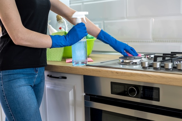 Jonge vrouw met wasvloeistof en doek wast en reinigt in de keuken