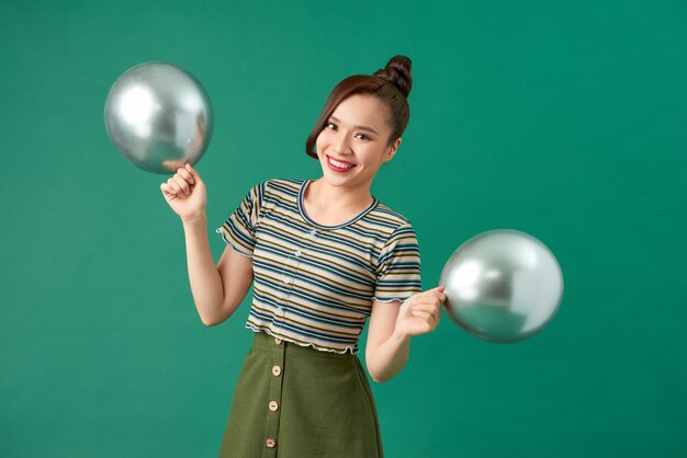 Jonge vrouw met zilveren ballons op groen
