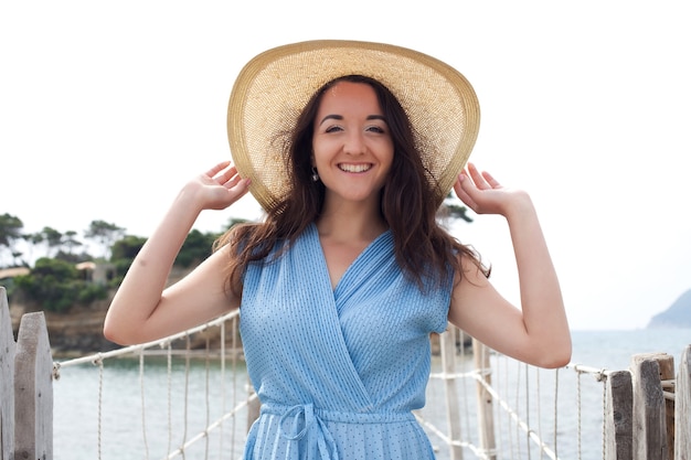 Jonge vrouw met zomerhoed die zich voordeed op de brug, prettige vakantie