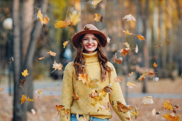 Jonge vrouw model in herfst park met gele bladeren esdoorn bladeren herfst seizoen mode