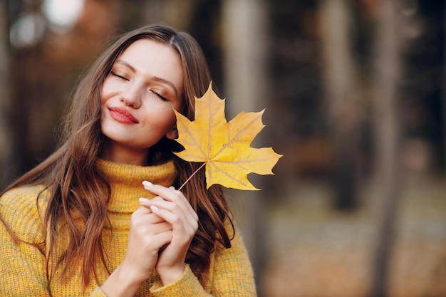 Jonge vrouw model in herfst park met gele bladeren esdoorn bladeren herfst seizoen mode