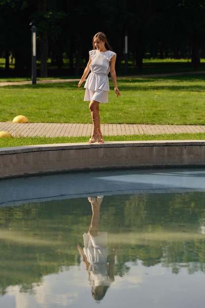 Jonge vrouw n gestippelde witte sundress poseren in het stadspark