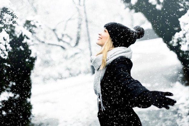 Jonge vrouw n warme kleren genieten in de sneeuw