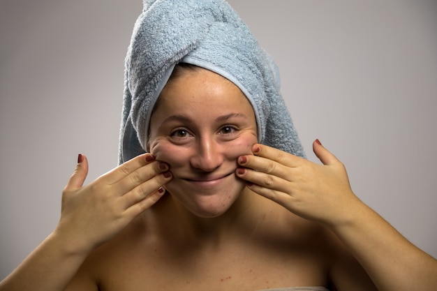 Jonge vrouw na douche met een handdoek en het glimlachen. Aanraken van zijn gezicht