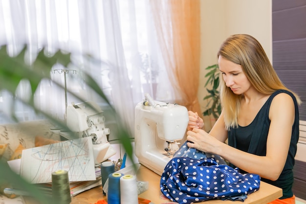 Jonge vrouw naait in haar kamer tussen kamerplanten