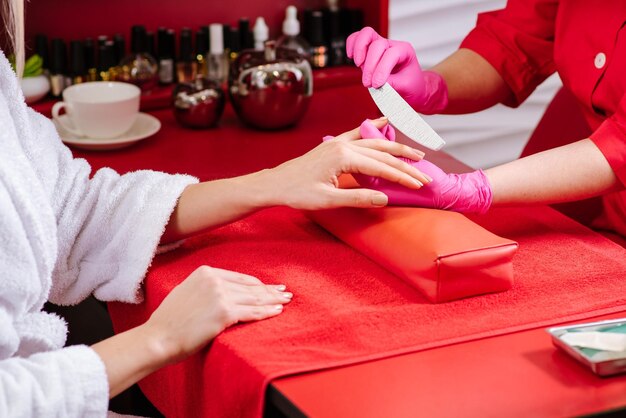 Jonge vrouw neemt manicurebehandeling in de schoonheidssalon